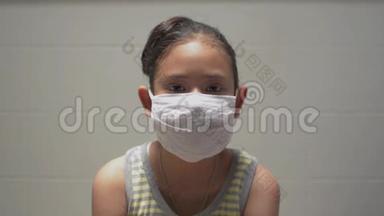 肖像亚洲可爱女孩在家期间戴着保护面具。 女少年展现自己的实力，看着镜头..